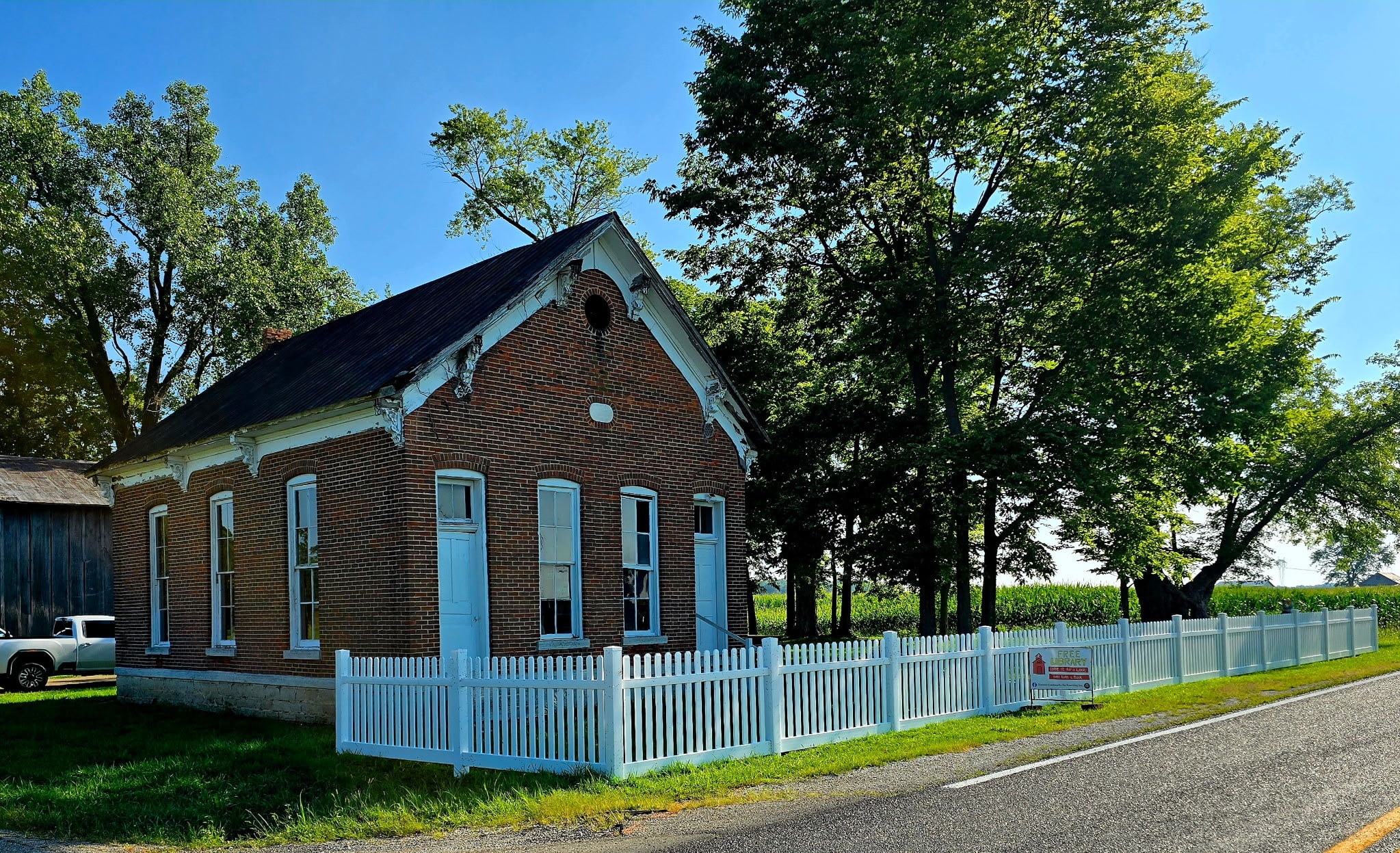 White vinyl picket fence surrounding a historic brick building